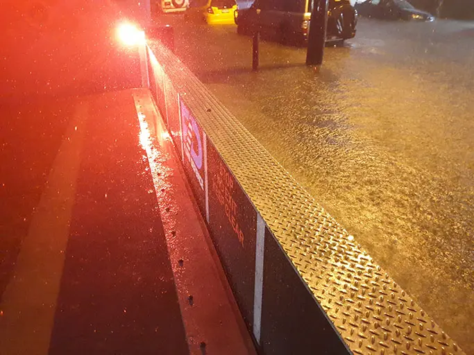 Activated self-activating flood barrier holding back floodwater during heavy rain