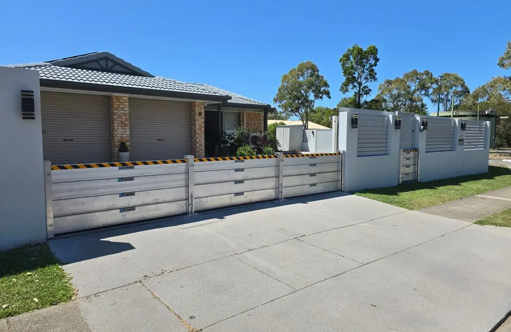 Demountable flood barrier installed across a residential driveway and entry gate